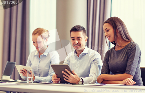 Image of smiling business people with tablet pc in office