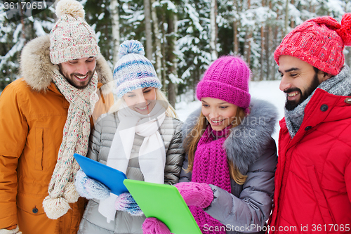 Image of smiling friends with tablet pc in winter forest
