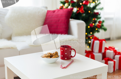 Image of close up of christmas cookies, sugar cane and cup