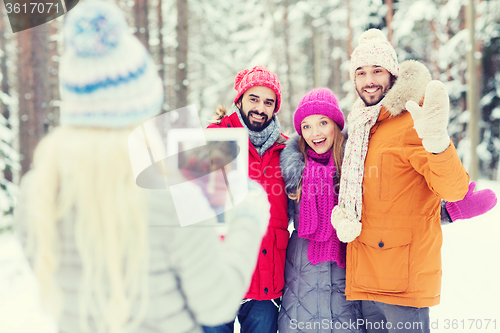 Image of smiling friends with tablet pc in winter forest