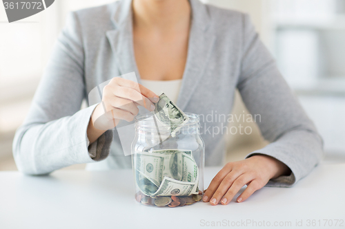 Image of close up of woman hands and dollar money in jar