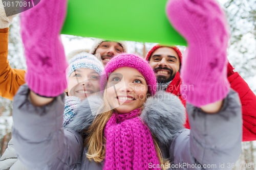 Image of smiling friends with tablet pc in winter forest