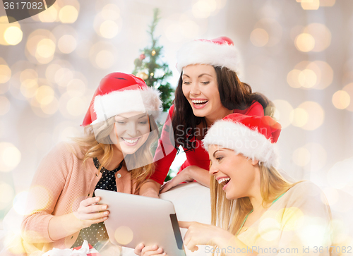 Image of happy women in santa helper hats with tablet pc
