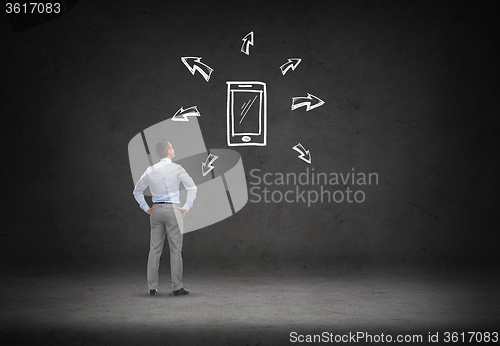 Image of businessman looking smartphone over concrete wall
