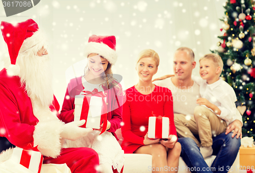 Image of smiling family with santa claus and gifts at home