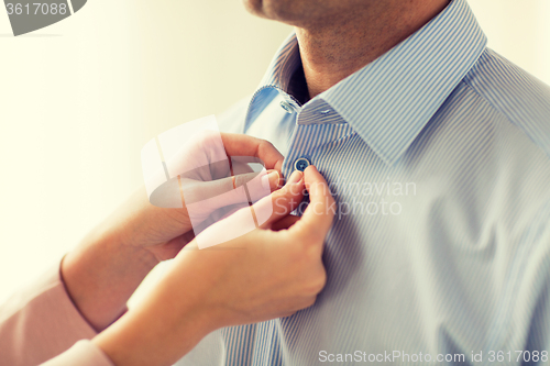 Image of close up of man and woman fastening shirt buttons