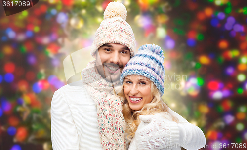 Image of happy couple in winter clothes hugging over lights