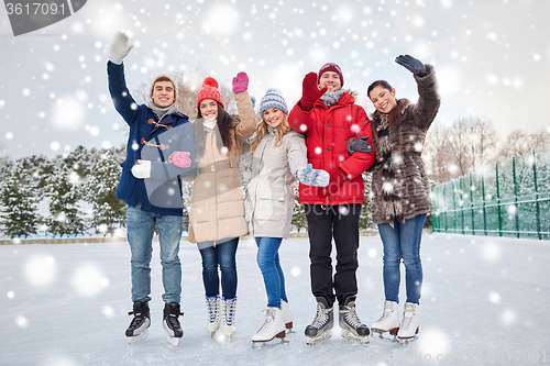 Image of happy friends ice skating on rink outdoors