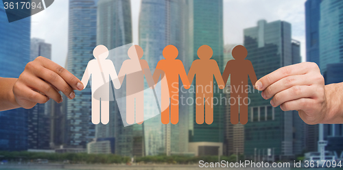 Image of hands with people pictogram over city background