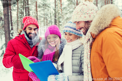 Image of smiling friends with tablet pc in winter forest