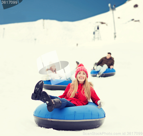Image of group of happy friends sliding down on snow tubes