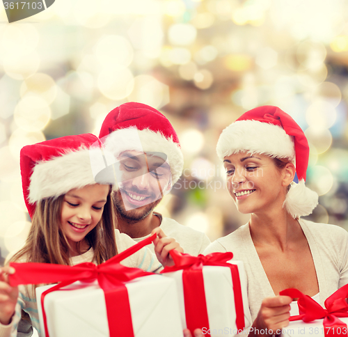 Image of happy family in santa helper hats with gift boxes