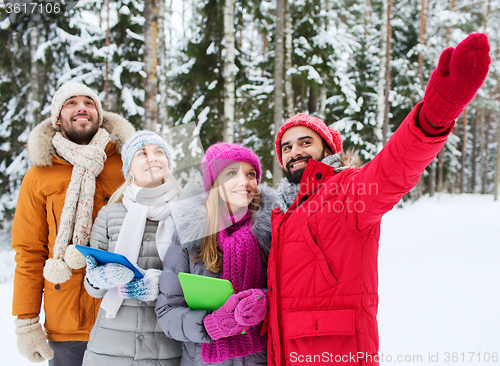 Image of smiling friends with tablet pc in winter forest