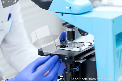 Image of close up of hands with microscope and blood sample