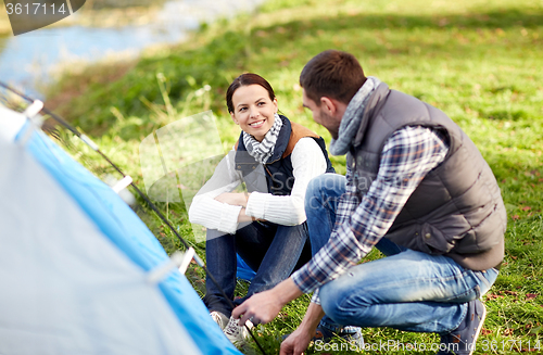 Image of happy couple setting up tent outdoors