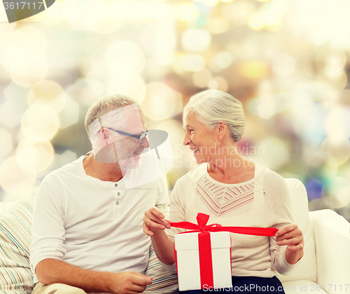 Image of happy senior couple with gift box at home