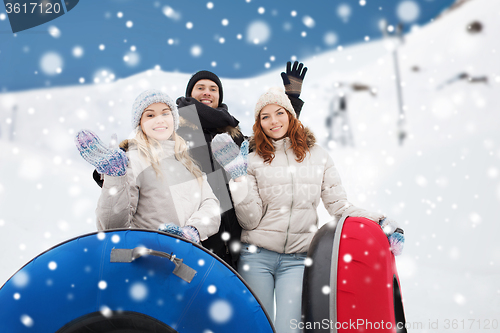 Image of group of smiling friends with snow tubes