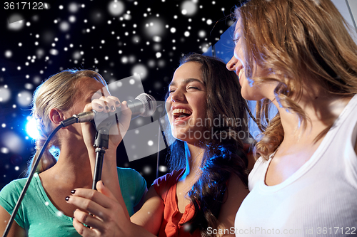 Image of happy young women singing karaoke in night club