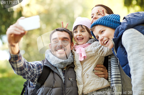 Image of family taking selfie with smartphone outdoors