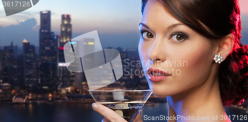 Image of woman holding cocktail over singapore night city