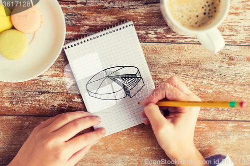 Image of close up of hands drawing chart in notebook