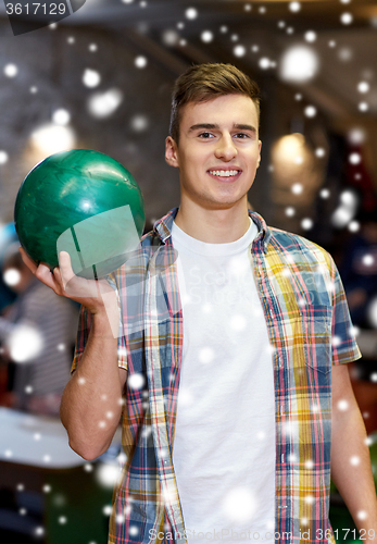 Image of happy young man holding ball in bowling club