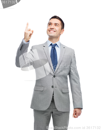 Image of happy businessman in suit pointing finger up