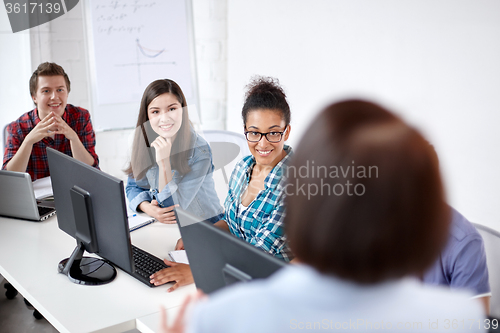 Image of happy students and teacher in computer class