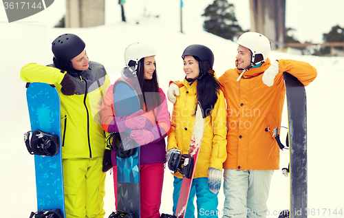 Image of happy friends in helmets with snowboards talking