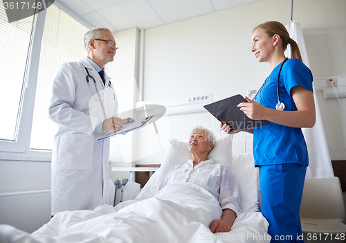 Image of doctor and nurse visiting senior woman at hospital