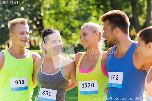 Image of happy friends or couple with racing badge numbers