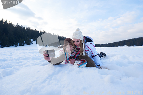 Image of romantic couple have fun in fresh snow and taking selfie