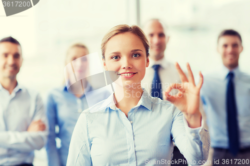 Image of smiling businesswoman showing ok sign in office