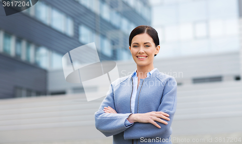Image of young smiling businesswoman over office building
