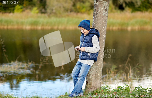 Image of happy boy playing game on smartphone outdoors