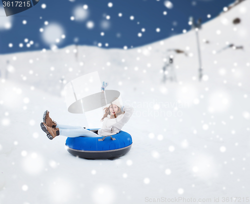 Image of happy teenage girl sliding down on snow tube