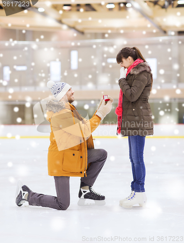 Image of happy couple with engagement ring on skating rink