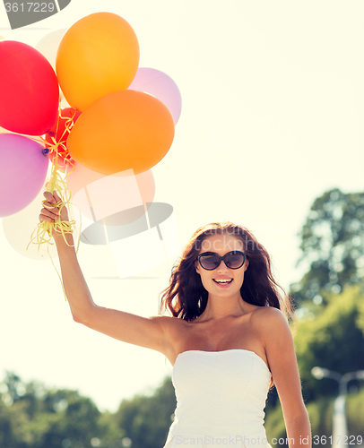 Image of smiling young woman in sunglasses with balloons