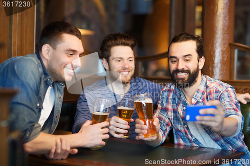 Image of friends taking selfie and drinking beer at bar