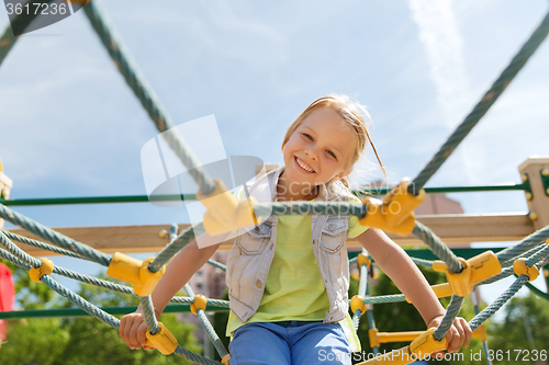 Image of happy little girl climbing on children playground