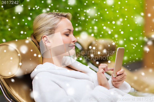 Image of beautiful young woman with smartphone at spa