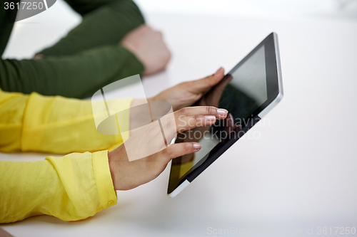 Image of close up of female hands with tablet pc at table