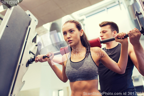 Image of man and woman with barbell flexing muscles in gym