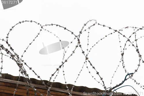 Image of barb wire fence over gray sky