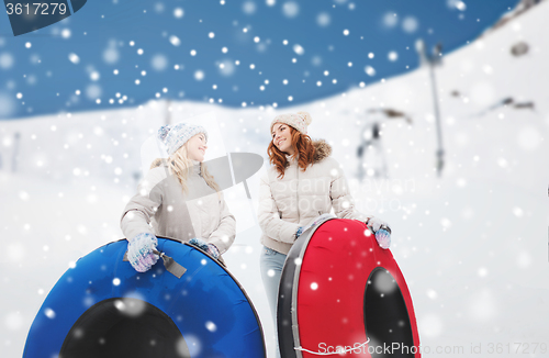 Image of happy girl friends with snow tubes outdoors