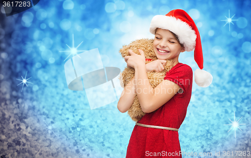 Image of smiling girl in santa helper hat with teddy bear