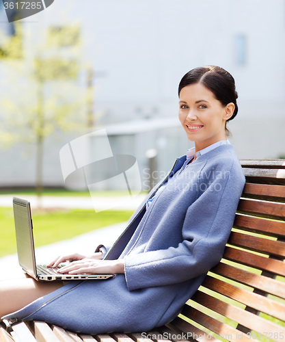 Image of smiling business woman with laptop in city