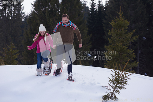 Image of couple having fun and walking in snow shoes