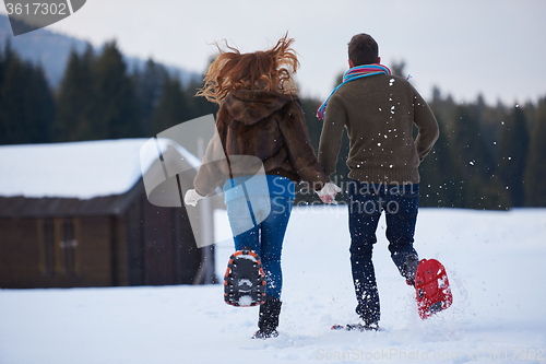 Image of couple having fun and walking in snow shoes