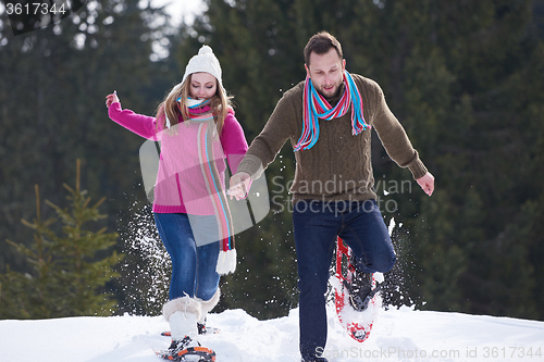 Image of couple having fun and walking in snow shoes